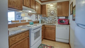Una cocina compacta con armarios de madera, estufa, microondas y lavavajillas.