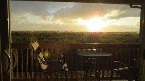 Un balcon offrant une vue sur le coucher de soleil et un paysage.
