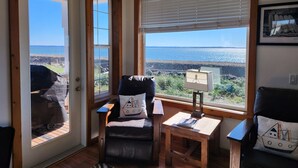 Une pièce confortable avec vue sur la mer, comprenant un fauteuil, une petite table et une lampe.