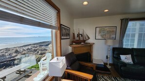 Un salon avec vue sur la plage, une cheminée et une carte accrochée au mur.