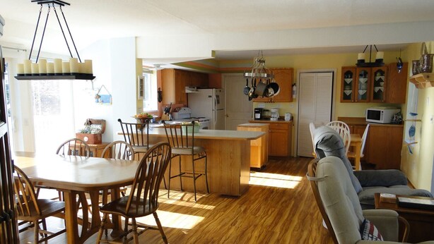 Una cocina amplia con armarios de madera, una isla central y un comedor con sillas y mesa de madera.
