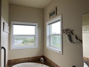 A bathroom with two windows, a bathtub, and a wall-mounted towel rack.