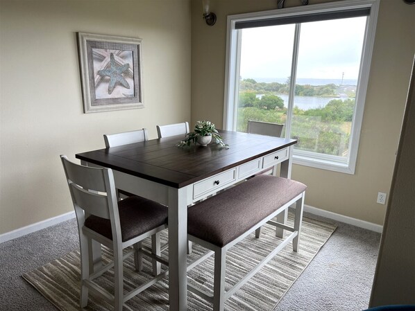 A dining area with a table, chairs, and a view of a lake through a window.