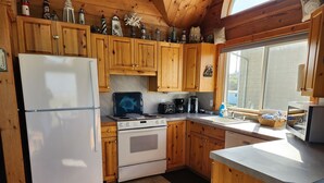 A kitchen with wooden cabinets, a refrigerator, a stove, and a window.