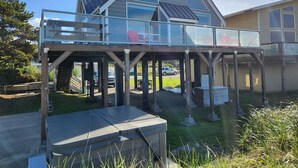 A modern house with a glass balcony, a covered outdoor seating area, and a clear view of the surrounding landscape.