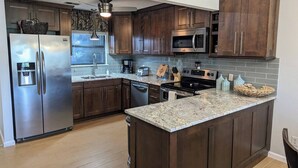 A modern kitchen with dark wood cabinets, stainless steel appliances, and a granite countertop.