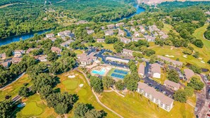 An aerial view of a residential area with houses, a golf course, and a dam in the background.