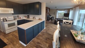 A modern kitchen with dark cabinets, a white countertop, and a built-in stove. - Sea Angel - Stunning views from this ocean front home ! (Moclips)