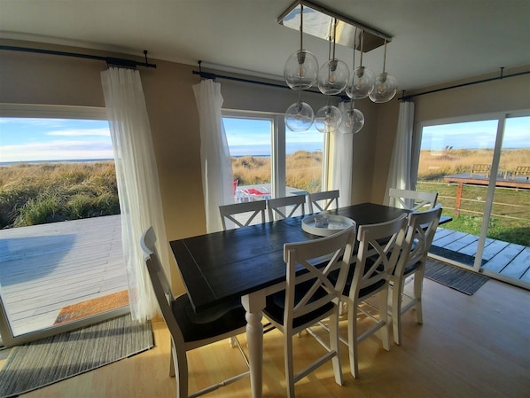 A dining area with a table and chairs, large windows with a view of the beach, and hanging light fixtures. - Sea Angel - Stunning views from this ocean front home ! (Moclips)