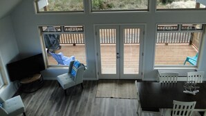 Una habitación amplia con un gran ventanal corredera que da a una terraza exterior.