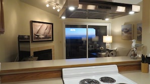 A modern kitchen with a white stove, a large window with a view, and a framed picture on the wall.