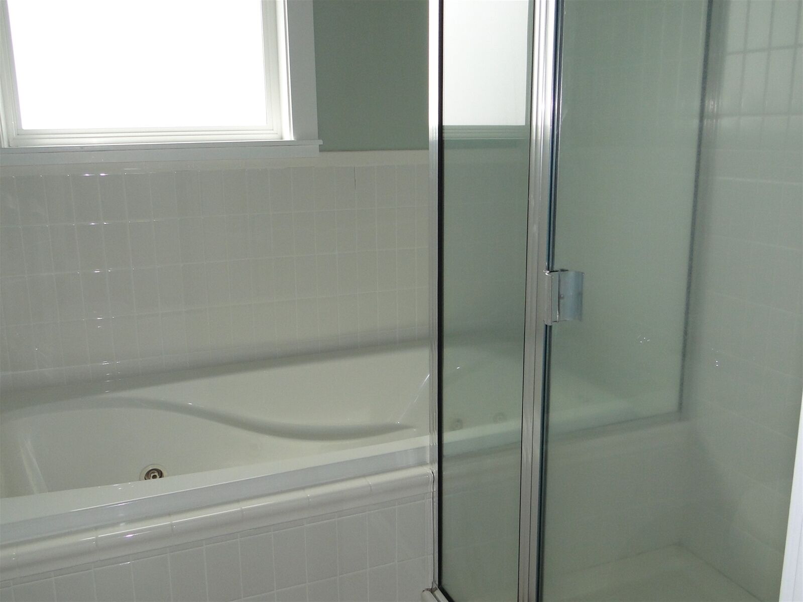 Un baño con ducha de vidrio y bañera blanca.