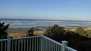 Une vue sur la côte, prise depuis une terrasse dotée d’une balustrade, avec l’océan et la plage en contrebas.