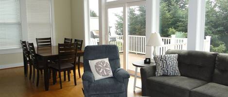 A spacious living room with a dining area, large windows, and a balcony.
