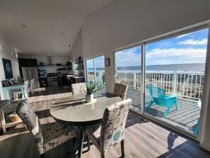 Eine moderne Küche mit Meerblick, ein Essbereich mit gemusterten Stühlen und ein Balkon mit türkisfarbenen Stühlen.