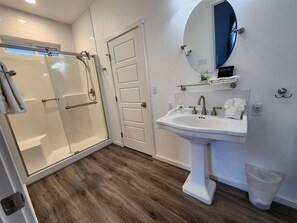 Ein modernes Badezimmer mit Glasdusche, Waschbecken in Weiß und einem Spiegel.