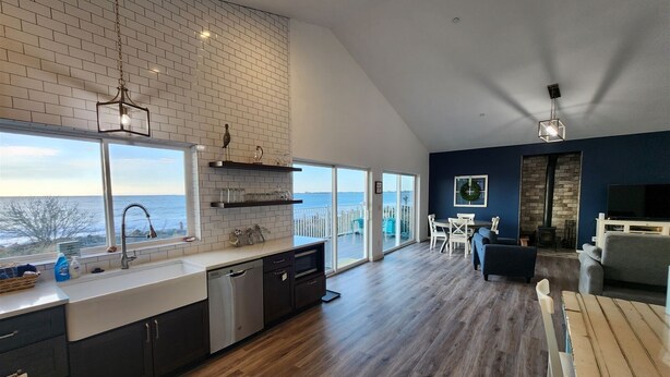 Una cucina moderna con un'ampia finestra vista mare, zona pranzo con vista e un accogliente soggiorno con camino.