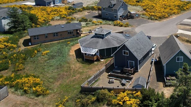 Uma área residencial costeira com casas, praia e arbustos floridos em tons de amarelo.