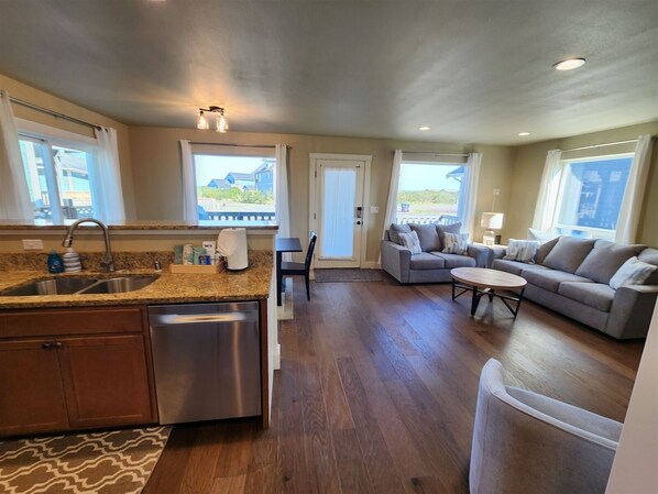 A spacious living area with a sofa, a coffee table, and a kitchen with a sink and countertop.