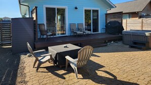 A light blue house with a covered patio, outdoor seating, and a hot tub. - Sand Dollar- Adorable 2 bedroom  with a Hot tub, fenced yard, BBQ and pets ok . (Ocean Shores)
