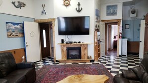 Ein Wohnzimmer mit Kamin, Ledersofas, Fernseher und maritimer Dekoration.
