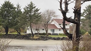 A house with a stone wall and a dock extending into a body of water. - Joe Creek Inn- Unique Home (Pacific Beach)