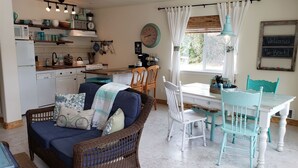 Een gezellige keuken met een eethoek, met rieten meubels, een klok en een bordje met de tekst 'Welcome to the Beach'.