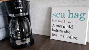 Een koffiezetapparaat en een bord met een woordspeling over een zeemeermin.