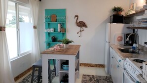 Eine Küche mit türkisfarbenen Regalen, einem Holztisch, einem Herd und einem Kühlschrank.