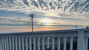 Ein Sonnenuntergang über einem Gewässer mit einem Holzdeck im Vordergrund.