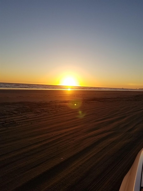 Une plage au coucher du soleil, sous un ciel dégagé.