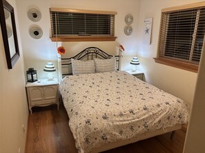 Una camera da letto con un letto, due comodini, un tavolino e una finestra con persiane, oltre a decorazioni alle pareti.
