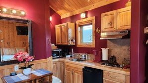 A compact kitchen with wooden cabinets, a microwave, a coffee maker, and a sink. - Moss Landing # 4 Studio (Ocean Shores)