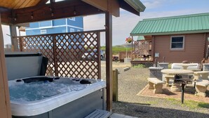 A hot tub with steps, a covered seating area, and a barbecue grill in a backyard setting. - Moss Landing # 4 Studio (Ocean Shores)