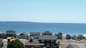 A coastal residential area with houses along the shoreline, a clear view of the sea, and a distant landmass. - Moss Landing # 4 Studio (Ocean Shores)