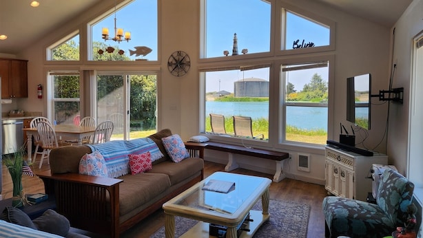 A spacious living room with large windows, a cozy sofa, a coffee table, and a television. - The Lake House - Best of both worlds (Ocean Shores)
