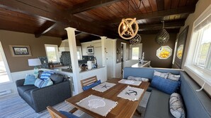 Un salon chaleureux avec une table à manger en bois, des coussins aux motifs bleus et blancs et un canapé bleu.