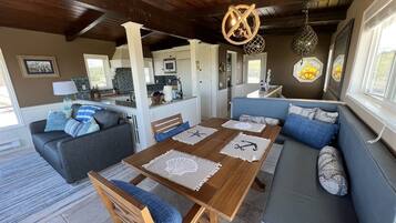 A cozy living area with a wooden dining table, blue and white patterned cushions, and a blue sofa.