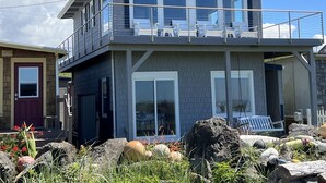 Un immeuble de deux étages doté d’un balcon, de grandes fenêtres et d’une façade en pierre.