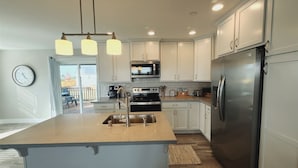 A modern kitchen with white cabinets, stainless steel appliances, and a central island.