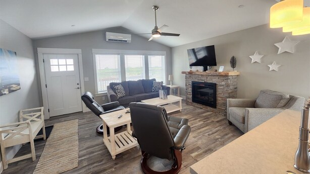 A spacious living room with a fireplace, a ceiling fan, and a TV mounted on the wall.