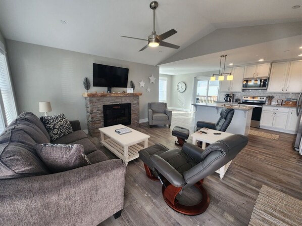 A modern living room with a fireplace, a flat-screen TV, a sofa, and a dining area with a table and chairs.
