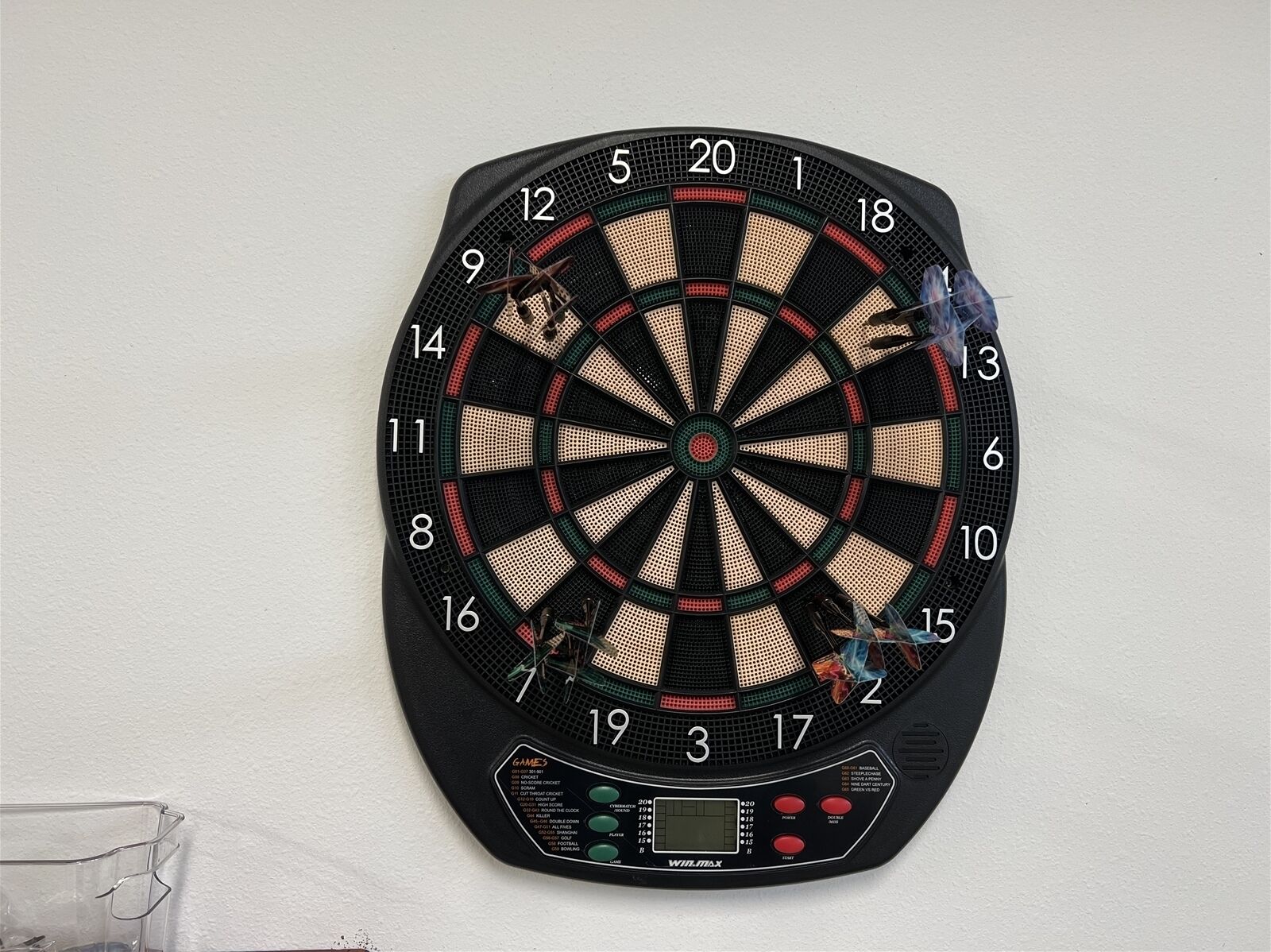 A dartboard mounted on a wall with a digital score display below it.