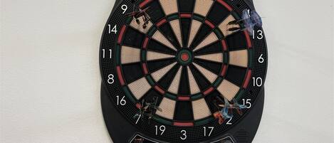 A dartboard mounted on a wall with a digital score display below it.
