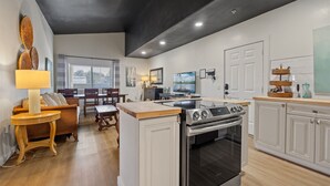 Una cocina moderna con horno empotrado, una zona de comedor con mesa y sillas, y vistas al exterior a través del ventanal.