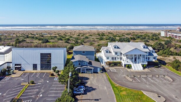 Un hotel frente al mar con estacionamiento, un edificio grande y una casa con porche.