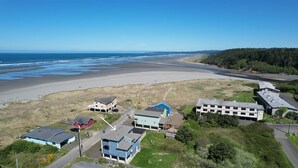 Eine Luftaufnahme einer Küstenregion mit Strand, Häusern und einer Straße.