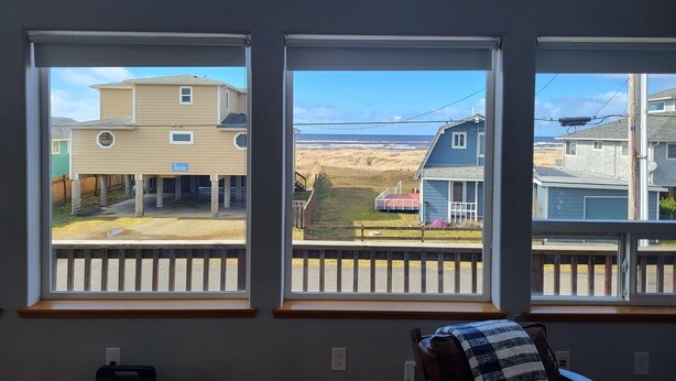 Ein Zimmer mit großen Fenstern mit Blick auf einen Strand und andere Gebäude.