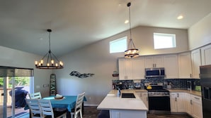A modern kitchen with white cabinets, a central island, and pendant lighting.