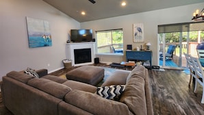 A spacious living room with a fireplace, a television, and a ceiling fan.